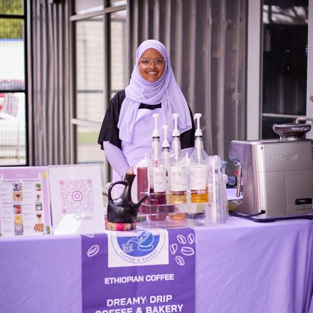 Amaturahaman smiling behind the Dreamy Drip coffee and bakery stand