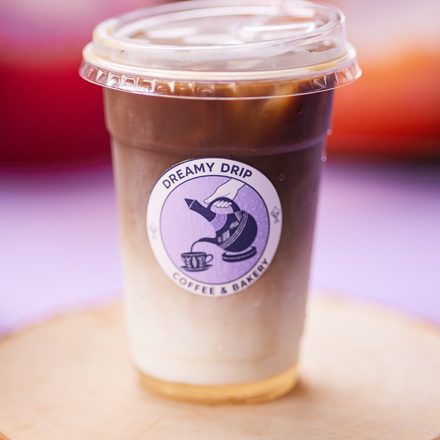 A layered Dreamy Drip iced coffee on a wood slice