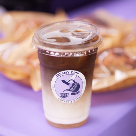 A Dreamy Drip iced coffee with fresh pastries behind it